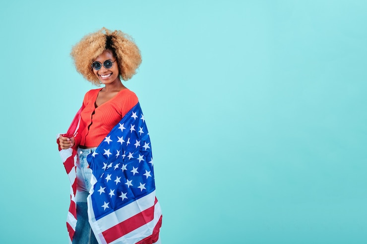 Photo smiling afro woman holding an usa flag while standing on an isolated background. usa independence day and patriotism concept.
