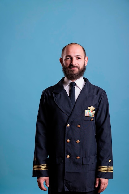 Smiling airplane captain wearing uniform medium close up\
portrait, plane aviator looking at camera. middle age pilot with\
civil badge on professional suit, aircrew member