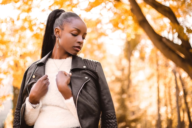 Smiling amazed african american woman dressed black leather jacket standing in the city park