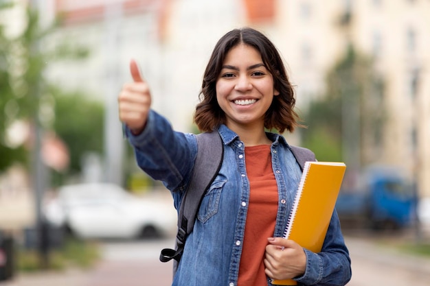 Smiling Arab Female Student Showing Thumb Up At Camera While Posing Outdoors