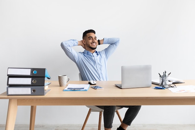 Smiling arab man leaning back sitting at desk