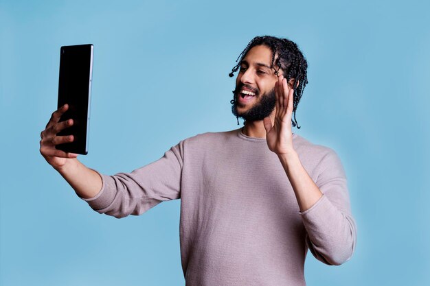 Smiling arab man waving hi during videocall on tablet person