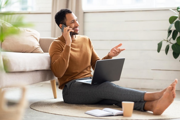 Smiling arab man working and talking on phone at home