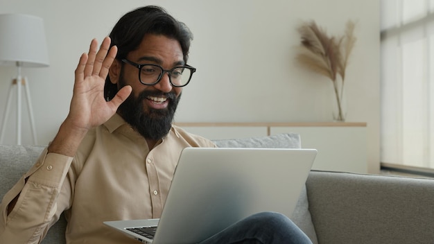 Smiling arabian indian muslim man talking virtual on laptop greet colleagues talk webcam video call