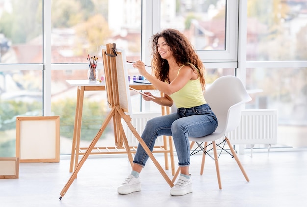 Foto pittura sorridente dell'artista sul cavalletto