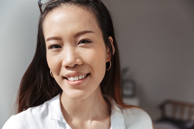 Smiling asian business woman looking at the front while standing near the window in office