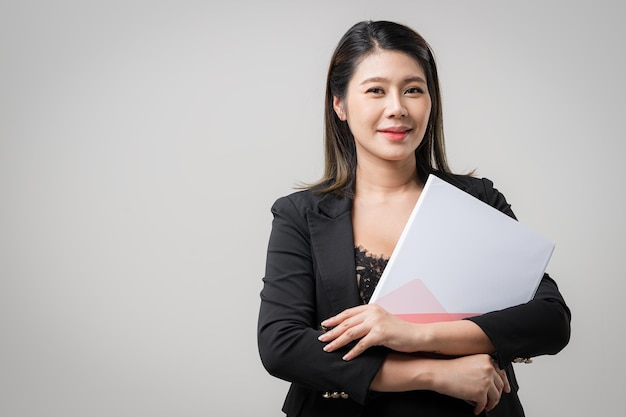 Фото Улыбающаяся азиатская деловая женщина, указывающая вверх и смотрящая в камеру на белом фоне