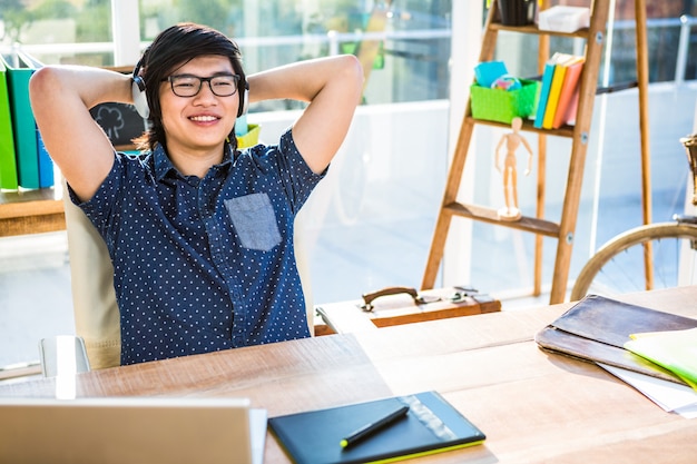 Smiling asian businessman listening to music in office