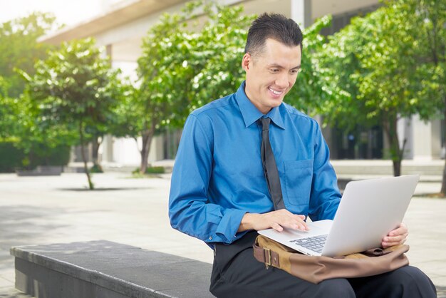 Smiling asian businessman using laptop