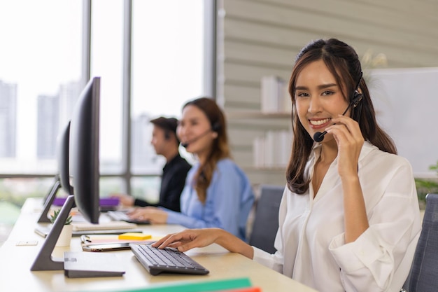 Photo smiling asian call center agent with headset working on support in the office