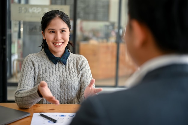 笑顔のアジア系女性会社員がアイデアを共有し、男性上司と仕事について話し合っている
