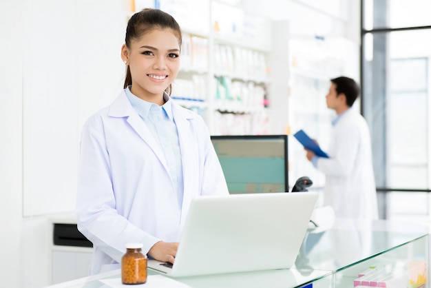 Smiling Asian female pharmacist working in pharmacy