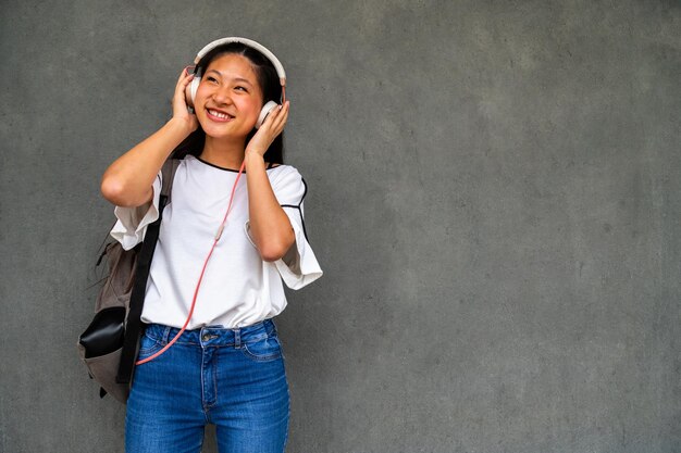 Photo smiling asian female teenager listening to music with headphones copy space