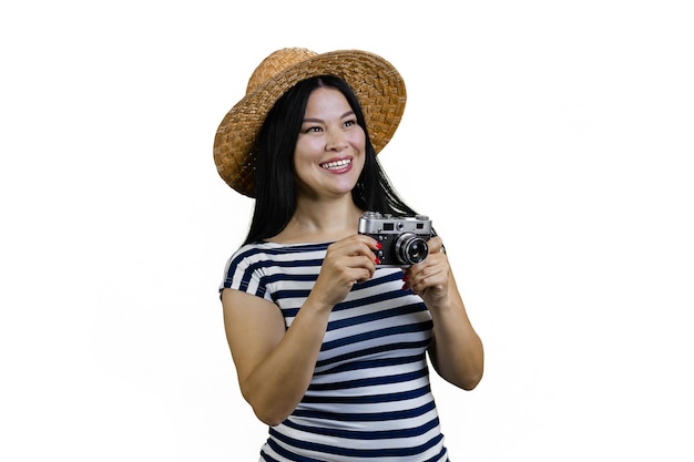 Smiling asian female tourist in straw hat is taking a photo a vintage photo camera isolated on white