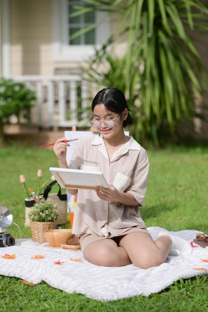 여름에 정원에서 즐겁게 그림을 그리는 웃는 아시아 소녀