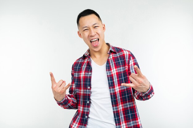 Smiling asian guy in a plaid shirt wide open shows fingers on an advertisement on an isolated white studio