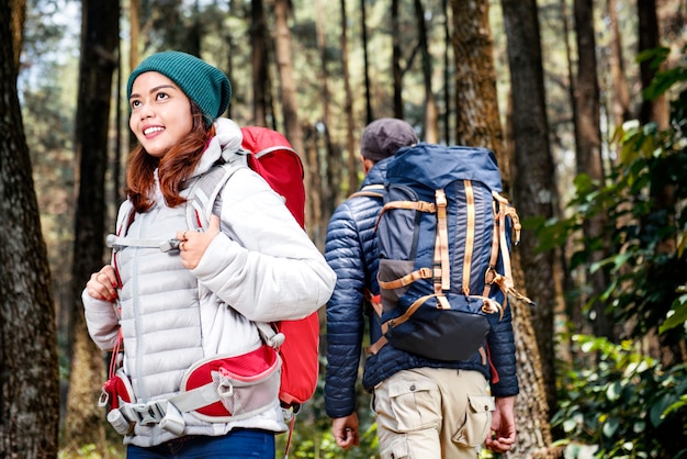 Усмехаясь азиатская женщина hikers исследуя с человеком hikers