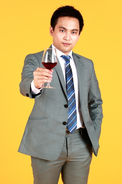 Smiling asian man holding a glass of wine to celebrate the best\
day is the wedding day in yellow background at studio. concept\
celebration lovely love.