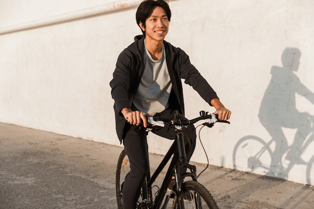 屋外で自転車に乗って笑顔のアジア人男性