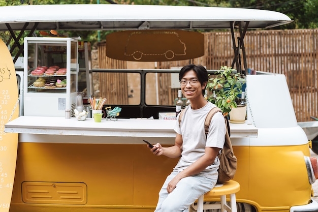 Smiling asian man using mobile phone