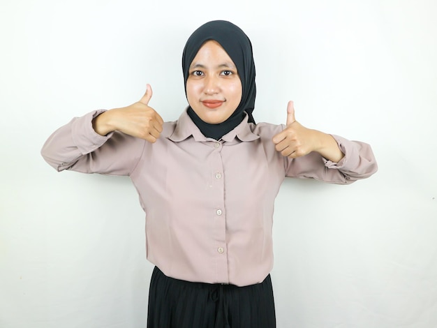 Smiling asian muslim woman in hijab showing thumb up in approval recommending like something good