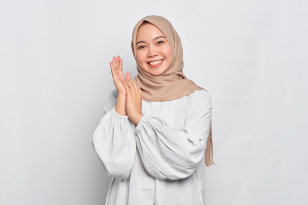 Smiling Asian Muslim woman rubs hands feels joyful isolated over white background