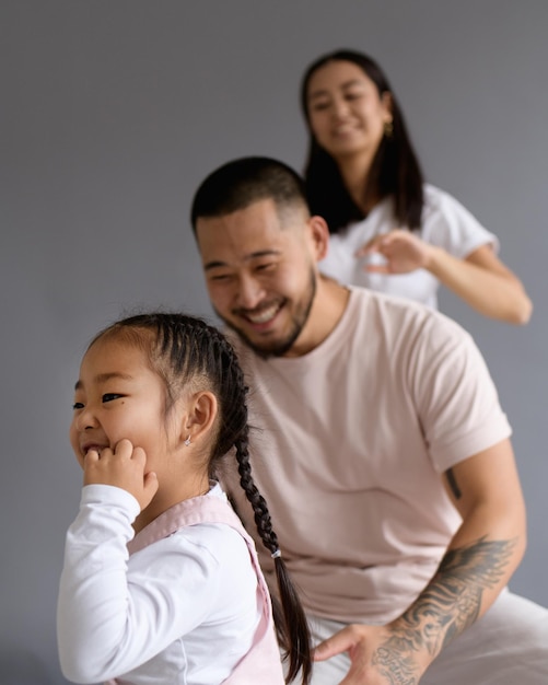 Photo smiling asian toddler child standing near blurred parents isolated on grey