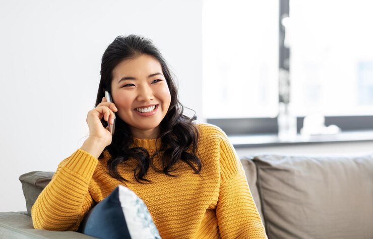 Photo 家でスマートフォンで電話している笑顔のアジア人女性