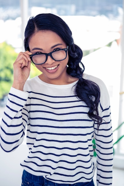 Smiling Asian woman holding eyeglasses and looking at the camera