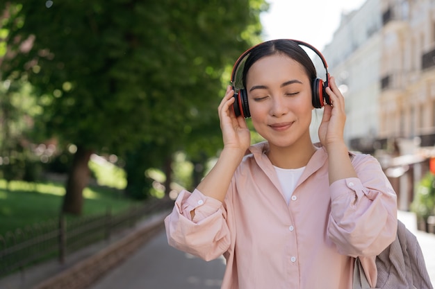 通りで目を閉じて音楽を聴いて笑顔のアジアの女性