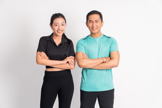 Smiling asian woman and man standing with hands crossed on isolated background