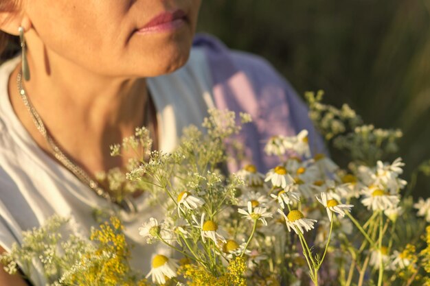 Smiling asian woman of older age in a summer park holding wild flowers the video conveys an