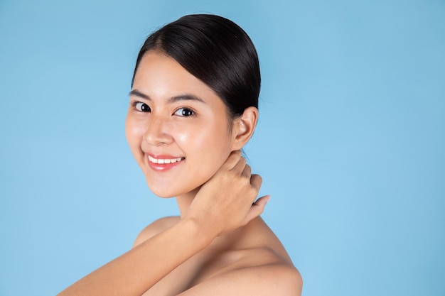 Smiling Asian woman touching healthy skin portrait. Beautiful happy girl model with fresh glowing.