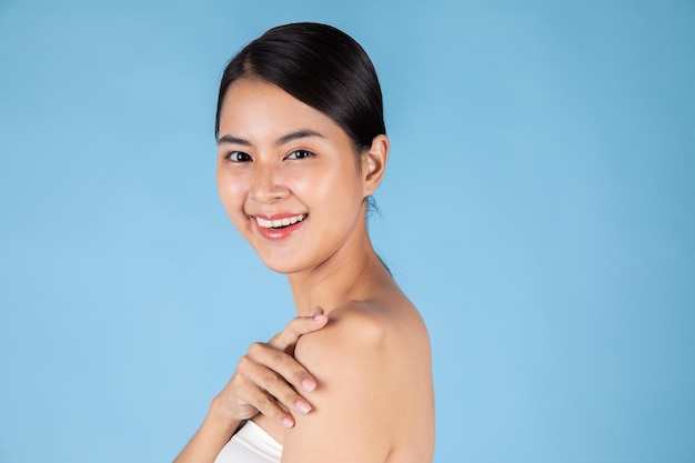 Smiling asian woman touching healthy skin portrait. beautiful happy girl model with fresh glowing.