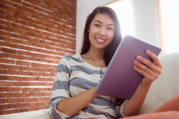 Donna asiatica sorridente che per mezzo della compressa sullo strato