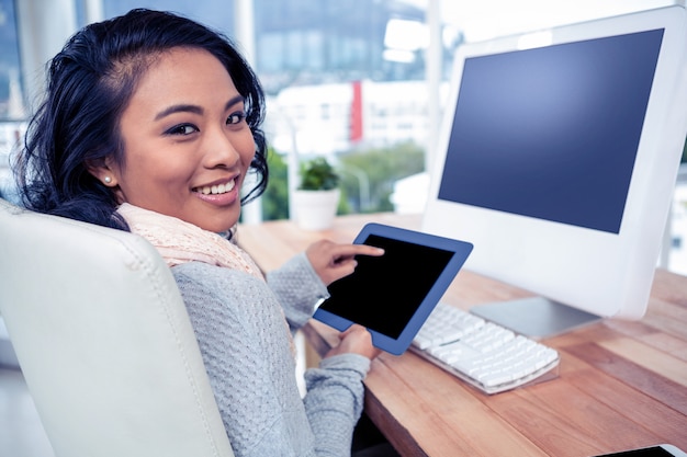 Smiling Asian woman using tablet in office