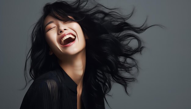 Smiling asian woman with wind in her black hair in studio