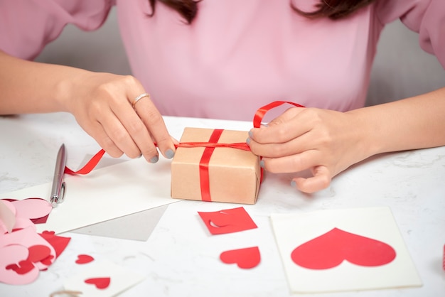smiling asian woman wrapping gifts for the holiday on living room background