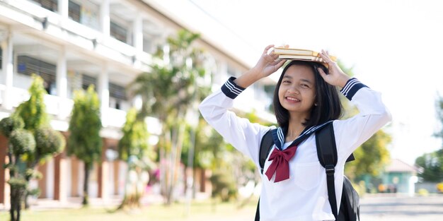 写真 笑顔のアジアの若い女の子が学校で制服を着て立っている