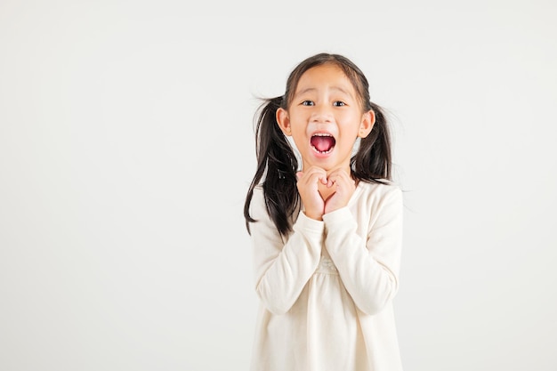笑顔のアジアの少女が白い背景に指と手でハートの形を作る自信を示していますバレンタインに愛を送る幼稚園児の肖像画