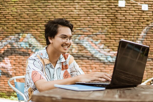 Smiling asian young man using laptop