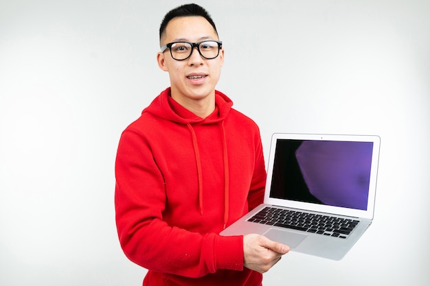 Smiling attractive brunette man demonstrates a blank laptop screen with mockup in his hands on a white studio background.