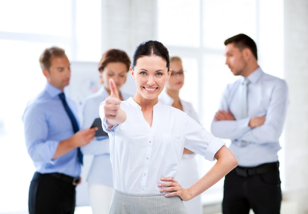 smiling attractive businesswoman in office showing thumbs up