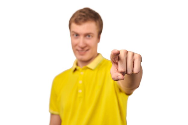 Smiling attractive handsome guy in casual yellow Tshirt pointing forward isolated white background