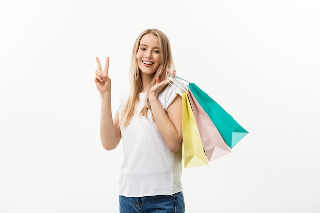 Smiling attractive woman holding shopping bags doing peace sign 