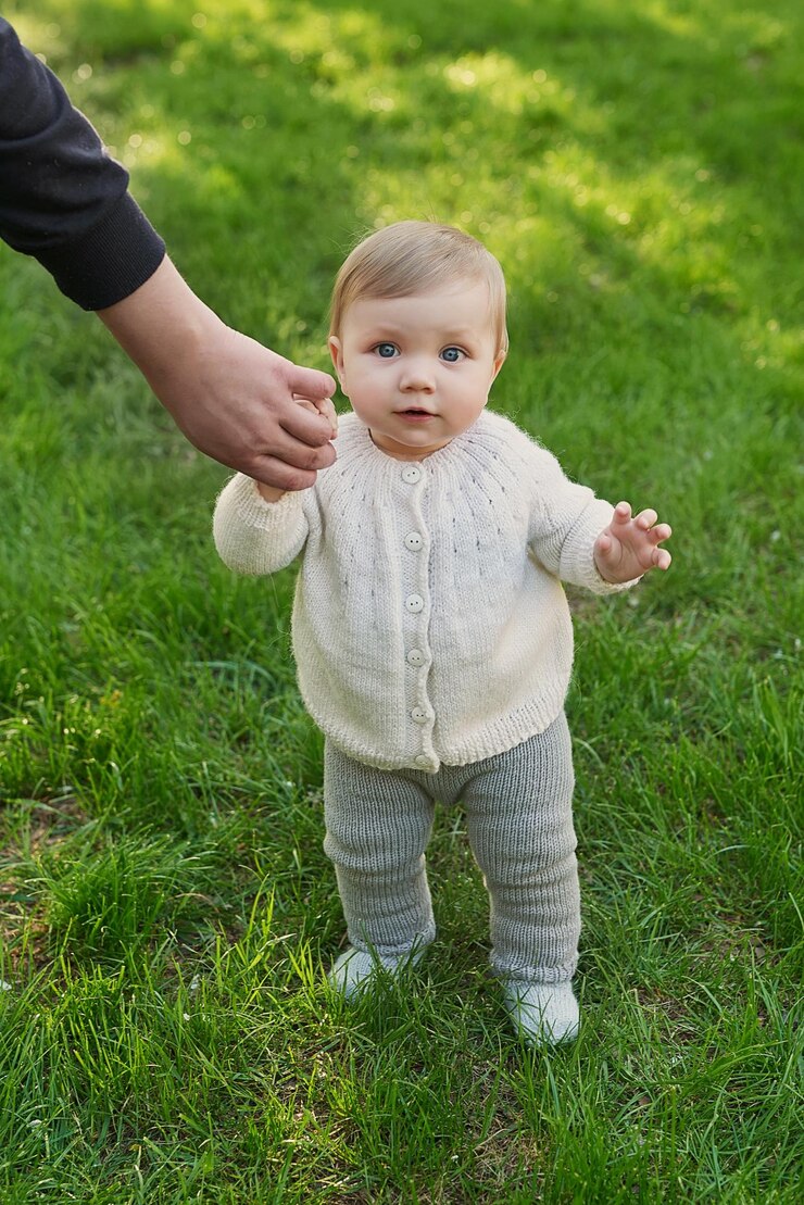 Smiling baby boy on grass in park Children Protection Day World Children's Day Father holds child by hand First steps
