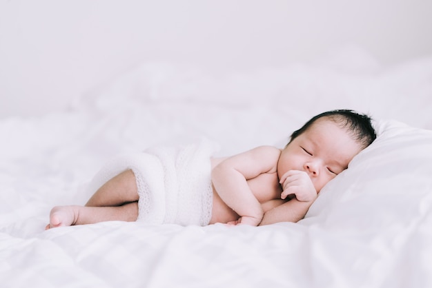 Smiling baby boy lying on a white bed