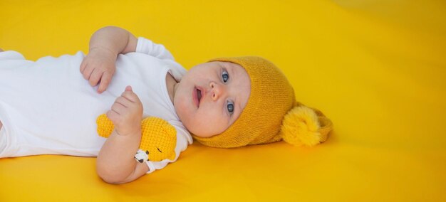 smiling baby girl goes to sleep with a teddy bear on a yellow background children