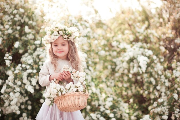 Smiling baby girl holding basket with flowers outdoors