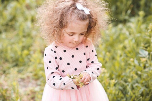 Smiling baby girl with flower in meadow